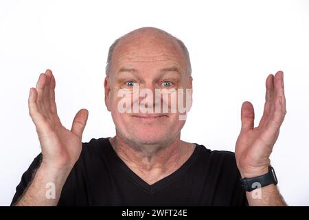 Smiling Middle-Aged Man in Black T-Shirt with Hands Raised on White Background - Happy Lifestyle Concept Stock Photo