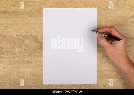 Creative Workspace: Top-Down View of Hand Drawing with Pen on Upright White Paper on Wooden Table, Copy Space.. Stock Photo