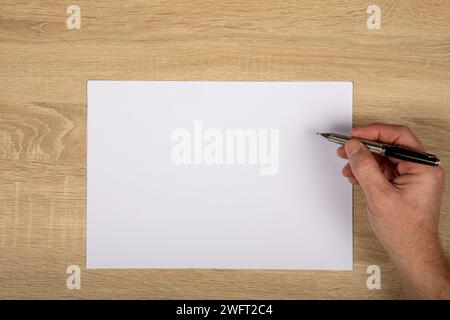 Creative Workspace: Top-Down View of Hand Drawing with Pen on Horizontal White Paper on Wooden Table, Copy Space. Stock Photo