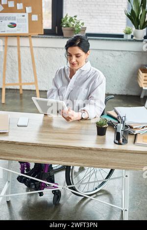 attractive devoted businesswoman with mobility disability in wheelchair working on her tablet Stock Photo