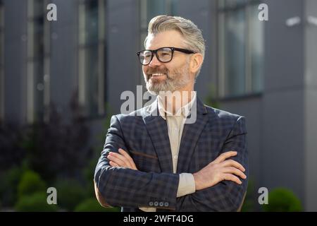 A professional mature senior businessman in a classy suit exudes confidence outside a corporate office setting. Stock Photo