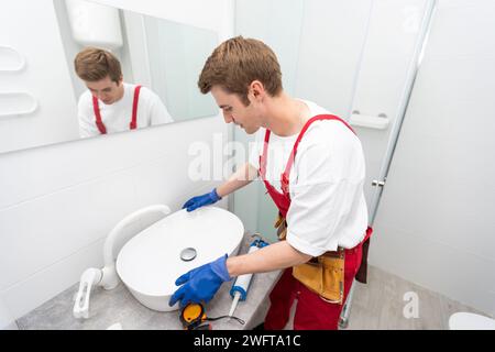 a worker installs a wash basin in a bathroom. Stock Photo