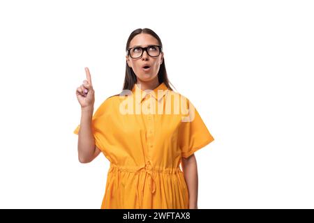 young pretty brunette lady dressed in yellow dress inspired by an idea Stock Photo