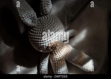 Brown knitted bunny sitting on a plush pillow Stock Photo
