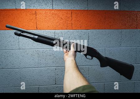 A shotgun in a man's hand against the background of a wall at a shooting range. High quality photo Stock Photo