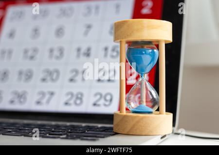 Time passing concept, time slipping away. Hourglass and the calendar Stock Photo