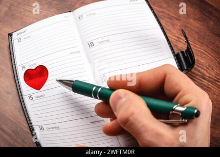 February 1, 2024: Hand Mark Valentine s Day on February 14 on a calendar with a red heart PHOTOMONTAGE *** Hand Markiert den Valentinstag am 14. Februar auf einem Kalender mit einem roten Herz FOTOMONTAGE Stock Photo