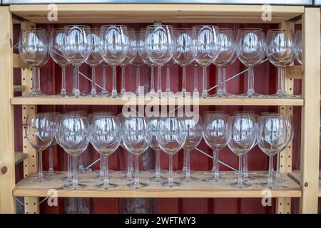 many empty wine glasses arranged on wooden shelves Stock Photo
