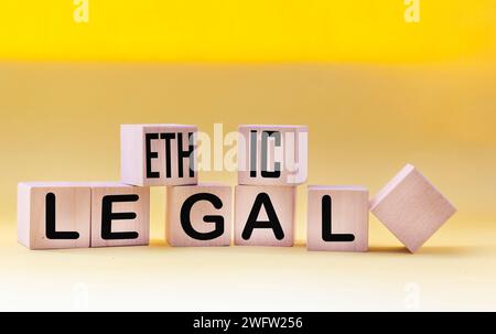 Ethical legal symbol. The words Ethical and Legal on wooden blocks and a beautiful yellow background. Business and ethical or legal concept. Copy spac Stock Photo