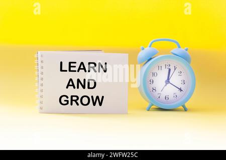 Learn and grow the symbol. Conceptual words Learn and Grow on notepad and yellow background with clock. Business, learning and growth concept. Stock Photo