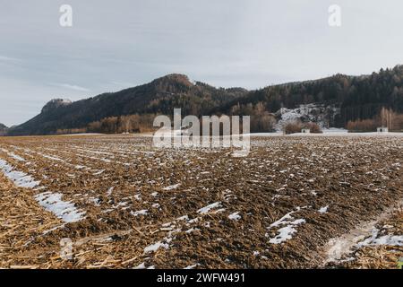 Snow-covered plowed field with distant mountains Stock Photo