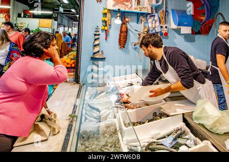 A fishmonger serving a customer at Florence Mercato Centrale , a busy popular,fresh food and produce market in Florence, Italy Stock Photo