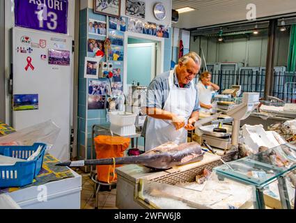 A fishmonger preparing a swordfish at Florence Mercato Centrale , a busy, popular fresh food and produce market in Florence, Italy Stock Photo