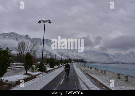 A cyclist rides along the snow covered road after snowfall in Srinagar, the summer capital of Jammu and Kashmir. Kashmir valley received fresh snowfall breaking the prolonged dry spell over the past two months. The Meteorological Department issued a prediction of cloudy weather during the daytime, accompanied by the likelihood of light to moderate rain and snow at various locations during the next 24 hours. Stock Photo