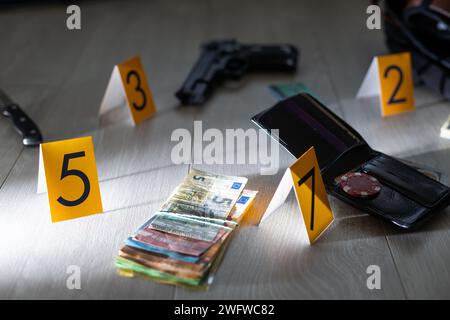 Crime scene investigation - numbering of evidences after the murdering in apartment. Brass knuckle, wallet and clothes with evidence markers Stock Photo