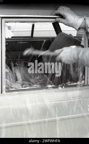 1970s, historical, a gloved car thef smashing a car window with a hammer, England, UK. Stock Photo