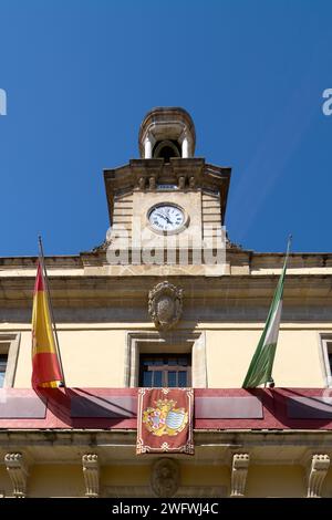 View of the Jerez de la Frontera Town Hall, with its clock tower and flags, under a clear blue sky Stock Photo