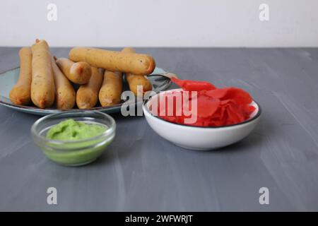 Red pickled ginger and spicy green wasabi sauce. Spicy sauces for meat on grey background with metos for copyspace text. Stock Photo