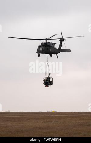 Artillery Soldiers with Alpha 'Gator' Battery, 3rd Battalion, 320th Field Artillery Regiment, 3rd Brigade Combat Team, 101st Airborne Division, 'Task Force 82,' conduct sling-load training at Mihail Kogalniceanu Air Base, Romania, Jan. 9, 2024. UH-60 Black Hawk helicopters from the 3rd Attack Helicopter Battalion, 1st Aviation Regiment, 1st Combat Aviation Brigade, 1st Infantry Division, supported the 101st Airborne Division Artillery Soldiers by moving M119 howitzers by air to increase proficiency in their warfighting tasks. Stock Photo