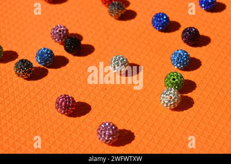 Beautiful, bright, multi-colored balls with Swarovski crystals chaotically arranged on a bright orange background. Stock Photo