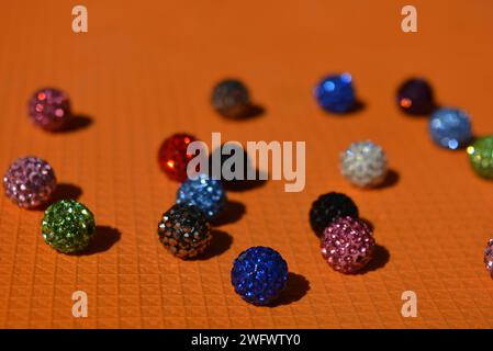 Beautiful, bright, multi-colored balls with Swarovski crystals chaotically arranged on a bright orange background. Stock Photo