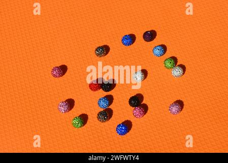 Beautiful, bright, multi-colored balls with Swarovski crystals chaotically arranged on a bright orange background. Stock Photo