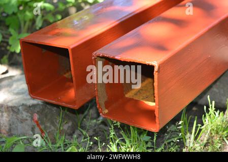 Building materials, equipment for construction and repair works. Long, thick, metallic profile covered with fresh brown fresh paint. Building profiles Stock Photo