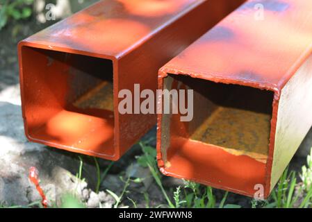 Building materials, equipment for construction and repair works. Long, thick, metallic profile covered with fresh brown fresh paint. Building profiles Stock Photo