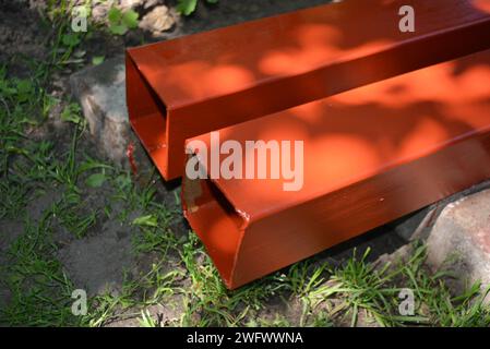 Building materials, equipment for construction and repair works. Long, thick, metallic profile covered with fresh brown fresh paint. Building profiles Stock Photo