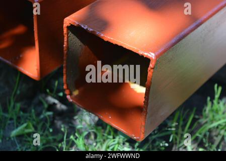 Building materials, equipment for construction and repair works. Long, thick, metallic profile covered with fresh brown fresh paint. Building profiles Stock Photo