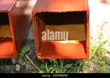 Building materials, equipment for construction and repair works. Long, thick, metallic profile covered with fresh brown fresh paint. Building profiles Stock Photo