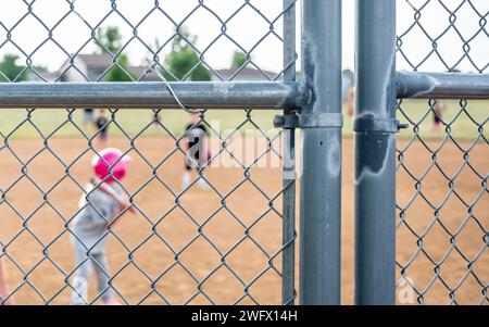 Defocused Parent view behind a chain link fence and home plate with a girl batter ready Stock Photo