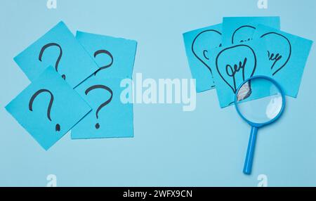 Drawn light bulbs on sheets of paper and a plastic magnifying glass, the concept of searching for new ideas Stock Photo