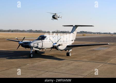 A C-12 Huron airplane is parked on the ramp while a UH-72 Lakota helicopter taxis by at Cairns Army Airfield Jan. 31, 2024. The C-12 is assigned to Detachment 1, Company B, 1st Battalion, 228th Aviation Regiment, U.S. Army Reserve, and is stationed at Fort Novosel, Alabama, the home of the U.S. Army Aviation Center of Excellence. Stock Photo