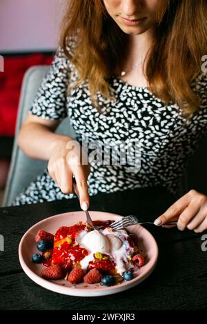 Young woman eating appetizing waffles waffle with ice cream and berries Stock Photo