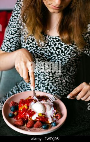 Young woman eating appetizing waffles waffle with ice cream and berries Stock Photo