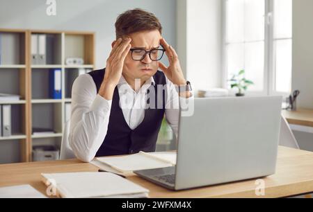 Frustrated young man looking at laptop screen, feeling tired with business deadline Stock Photo