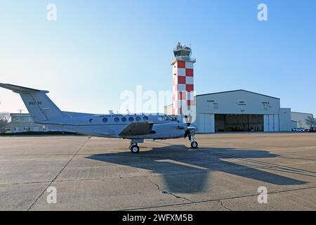 A C-12 Huron airplane assigned to Detachment 1, Company B, 1st Battalion, 228th Aviation Regiment, U.S. Army Reserve, Fort Novosel, Alabama, is parked in front of Cairns Army Airfield tower Jan. 31, 2024. Stock Photo