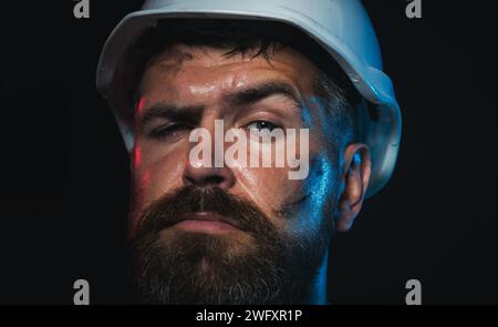 Closeup portrait of construction worker in hard hat. Serious male builder, architect or engineer in protective hardhat. Hard work. Bearded miner or Stock Photo