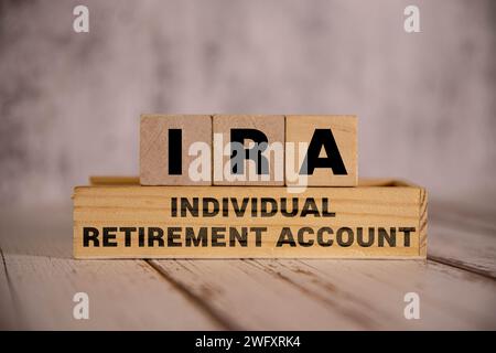 On a bright blue background, light wooden blocks and cubes with the text IRA Individual Retirement Account. Stock Photo