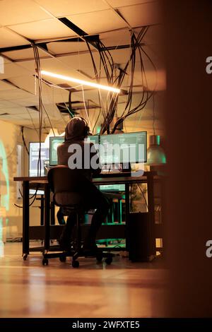 Female thief analyzing online codes to hack government database, attacking sensitive system and causing security breach. Spies hacking network and stealing information late at night. Stock Photo