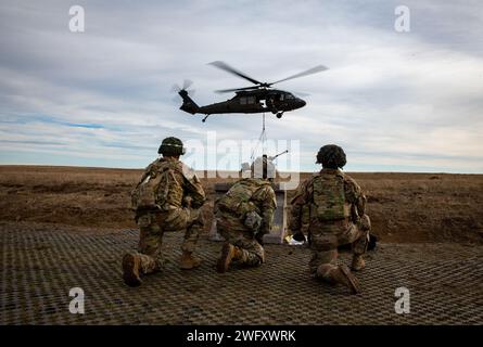 Artillery Soldiers from Bravo Battery, 3rd Battalion, 320th Field Artillery Regiment, 3rd Brigade Combat Team, 101st Airborne Division conduct sling-load operations and elevator drills with 3rd Attack Helicopter Battalion, 1st Aviation Regiment, 1st Combat Aviation Brigade, 1st Infantry Division on Mihail Kogalniceanu Air Base, Romania, Jan. 4, 2024, to increase readiness and proficiency in air assault operations. Stock Photo