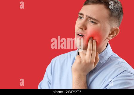 Young man having toothache on red background Stock Photo