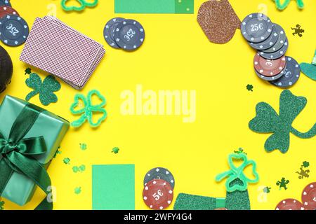 Frame made from poker chips, cards, gift box and decorations for St. Patrick's Day celebration on yellow background Stock Photo