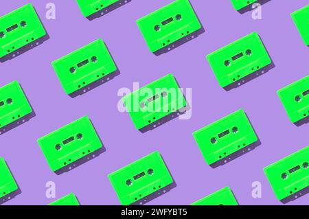 Pattern made with retro green audio cassette tapes on purple background. Creative concept of retro technology. 80's aesthetic. Vintage audio Stock Photo