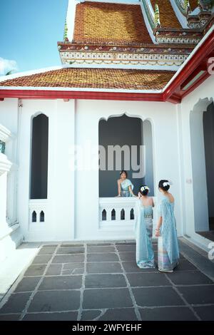 Asian family dressed in traditional Thai costumes shoot a video to upload to social media on the street of Wat Arun, a famous attraction in Bangkok, Y Stock Photo