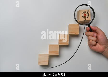 Hand holding magnifying glass focuses on the target icon. Business achievement goal concepts. Stock Photo