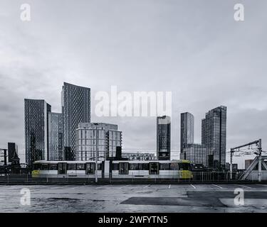 Bee Network tram in Manchester passing by the skyline of tall buildings at Deansgate Square Stock Photo