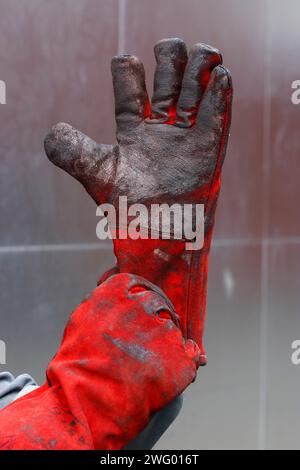 A male worker wearing red protective gloves on a construction site Stock Photo