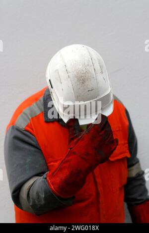 A tired worker after a shift in an orange jacket and helmet gently Stock Photo